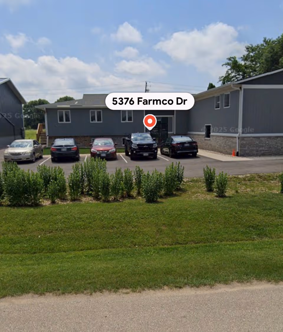 Front exterior of a gray, single-story care facility with several parked cars.