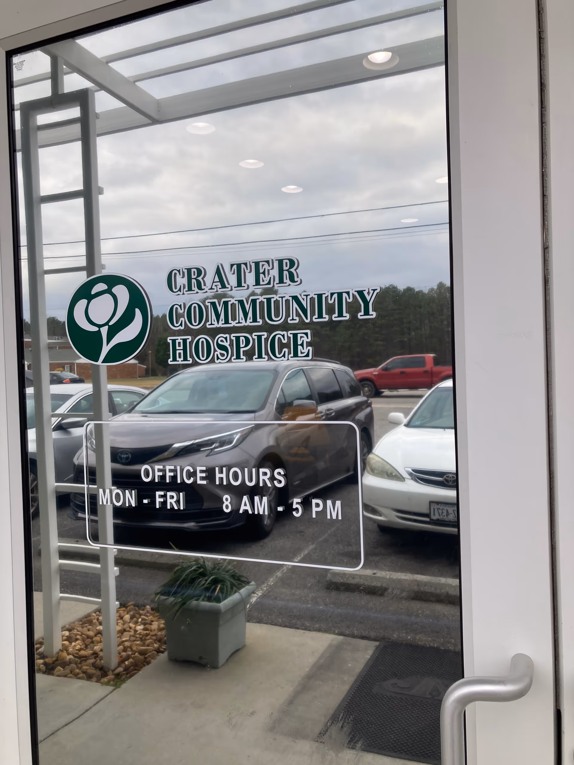 Glass entrance door with Crater Community Hospice sign and office hours
