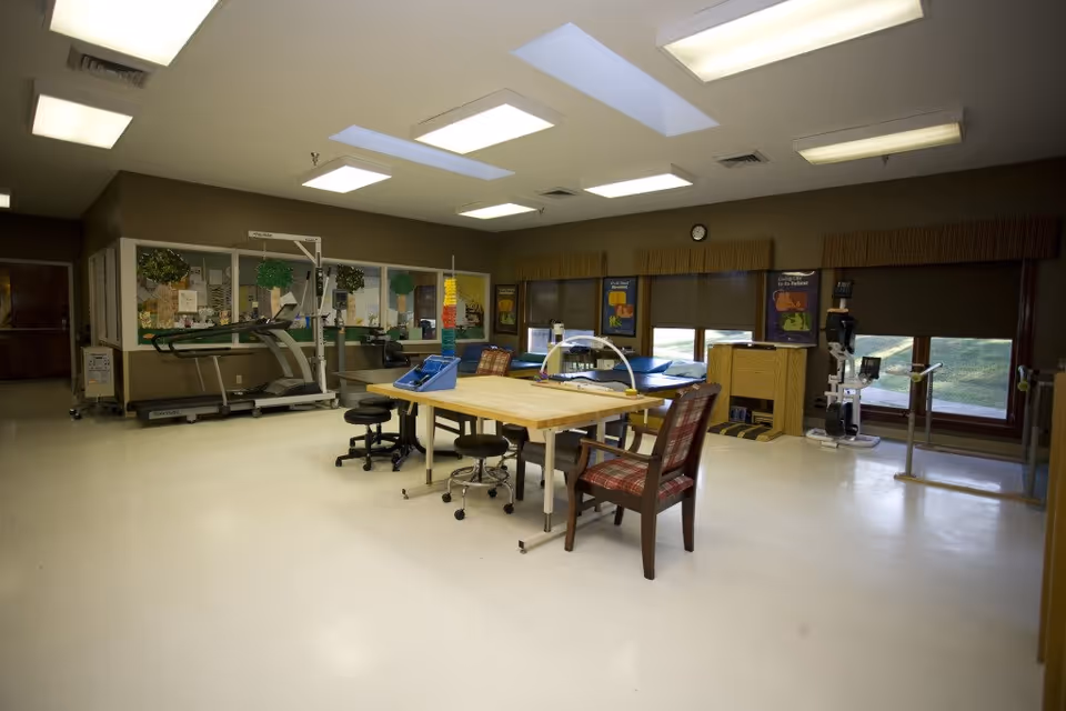 Indoor activity room with treadmill, large table, chairs, and exercise equipment.