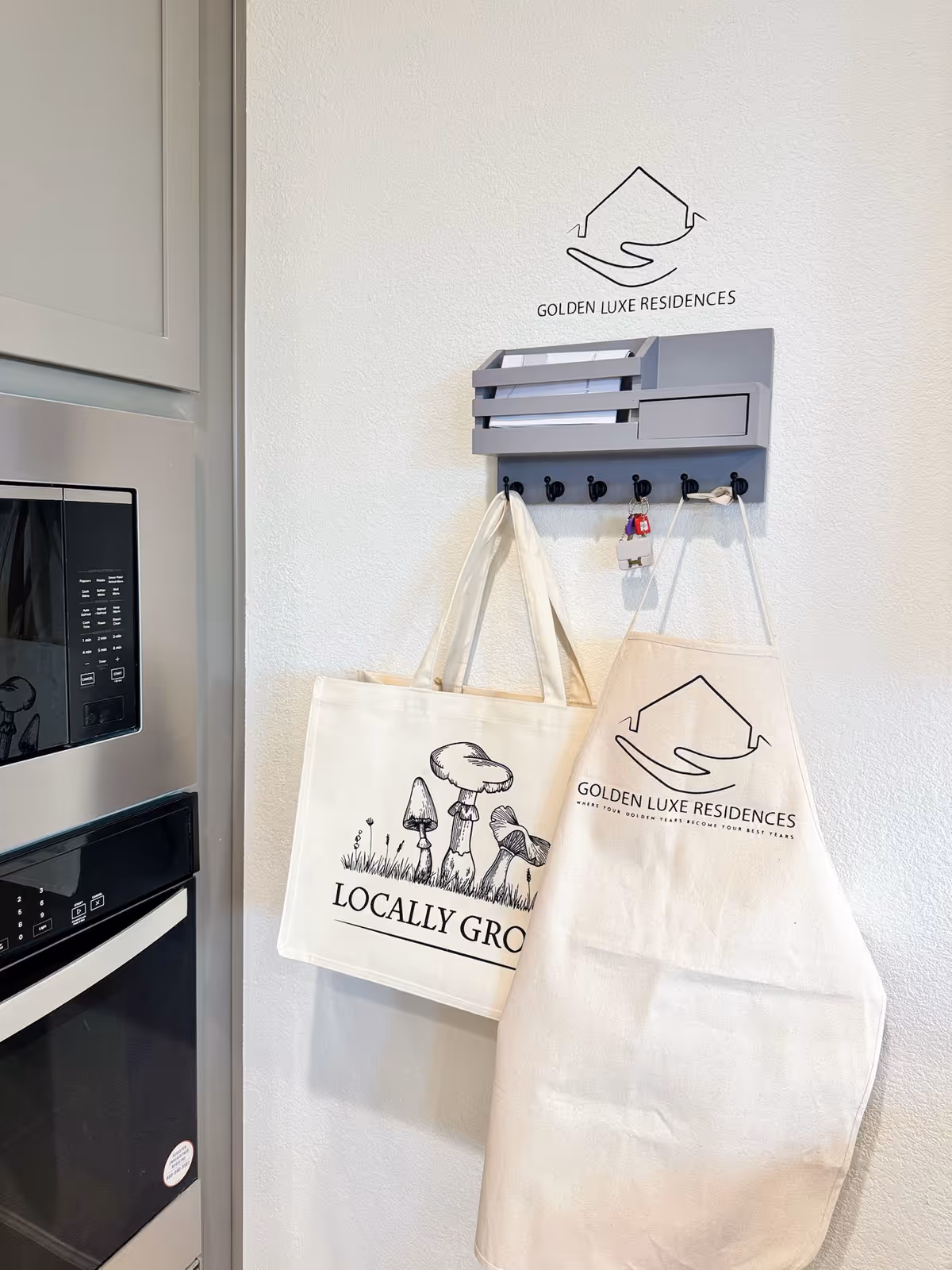 Interior wall showing Golden Luxe Residences logo, with a key rack and hanging tote bags.