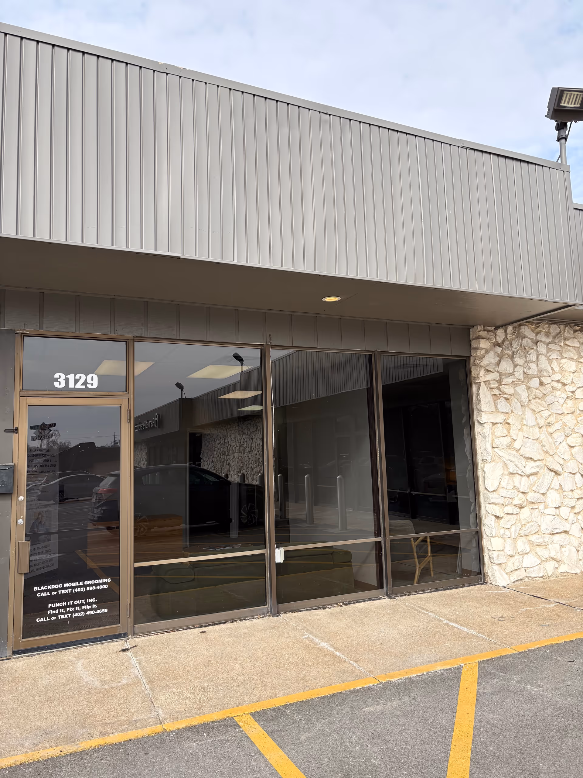 Front entrance of Kellah Home Care building with glass doors and stone wall.