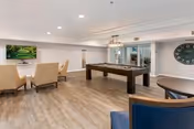 Modern lounge area with seating, a pool table, and a wall-mounted TV.
