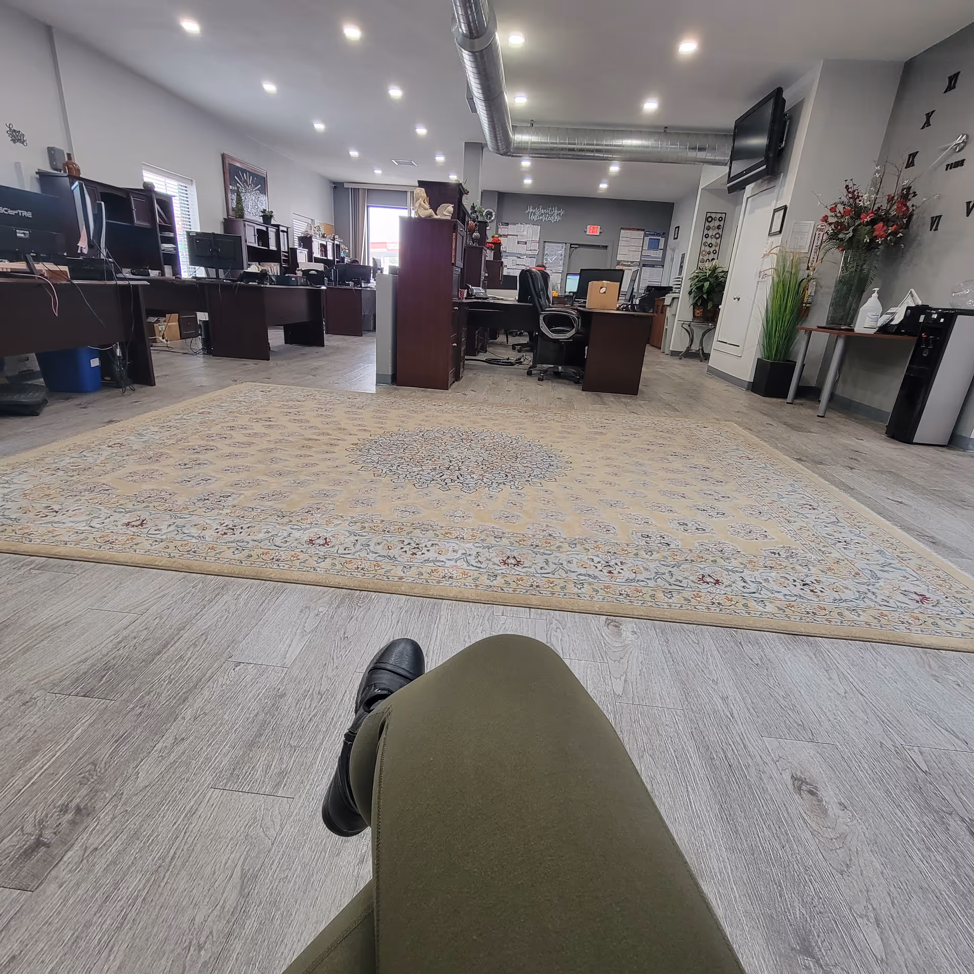 Office-like reception area with row of desks, computers, and a person's leg in foreground.
