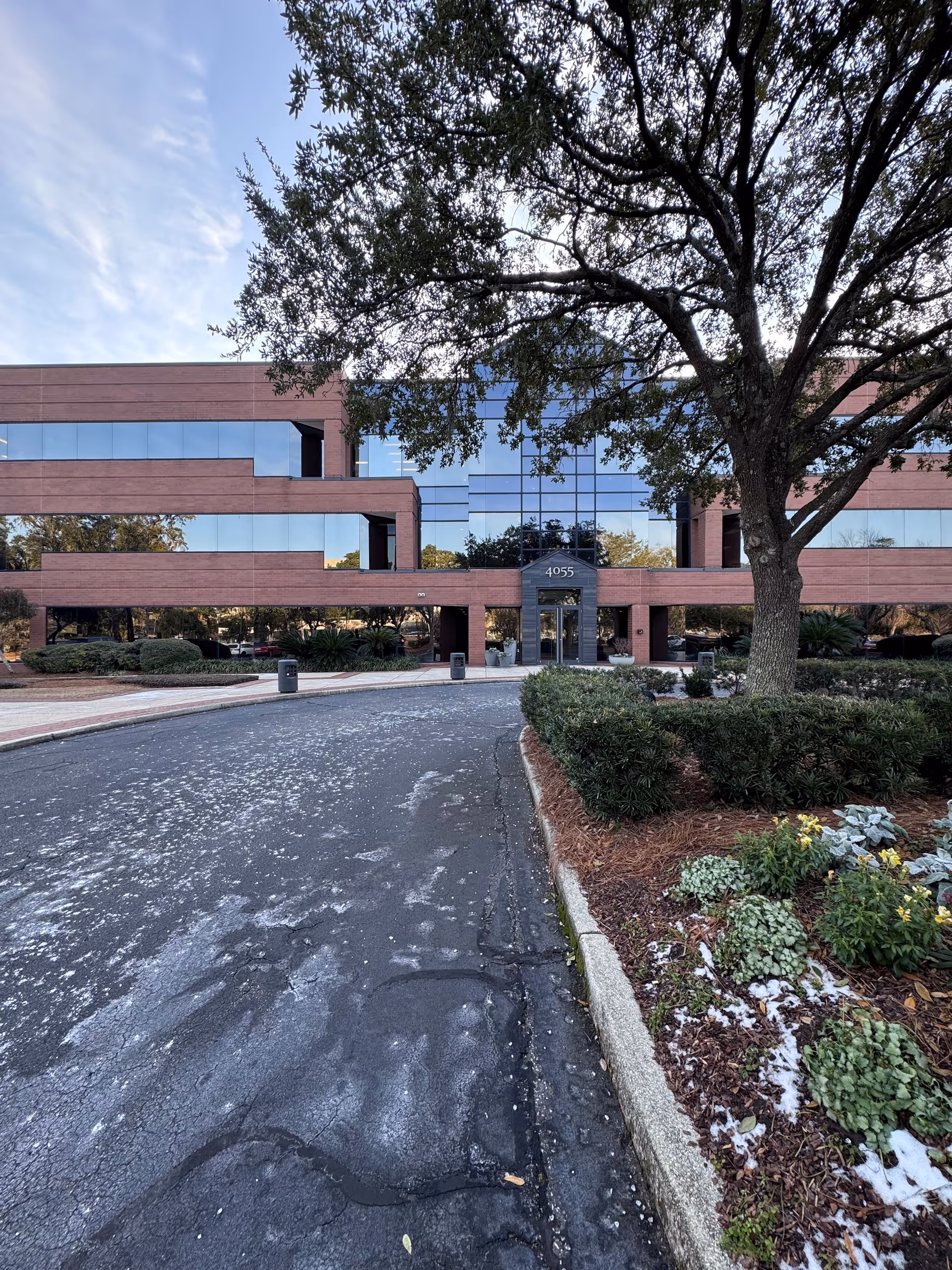 Exterior view of a brick office building with glass windows and a landscaped entrance.