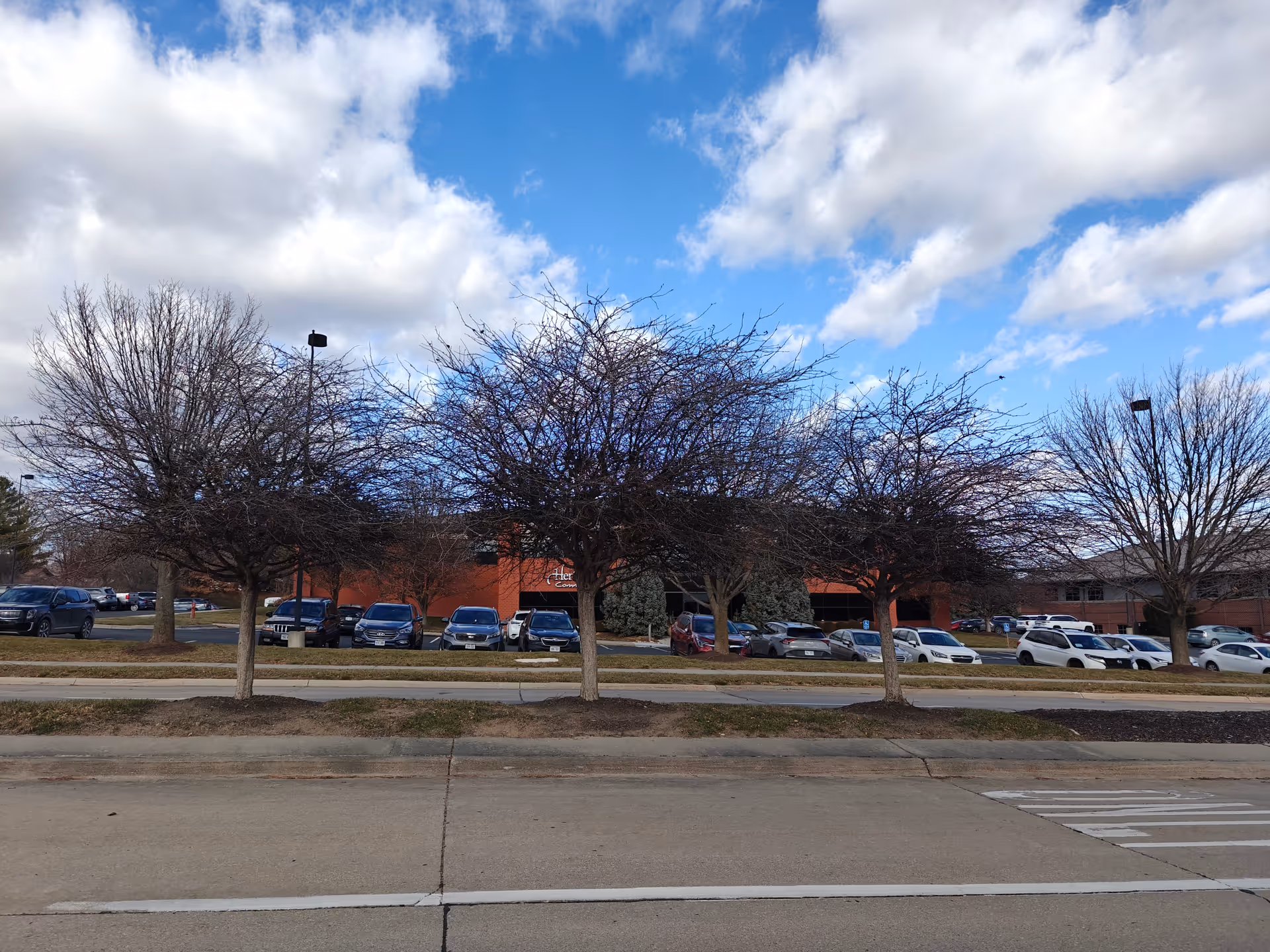Wide exterior view of a Heritage Communities senior living campus with parked cars.