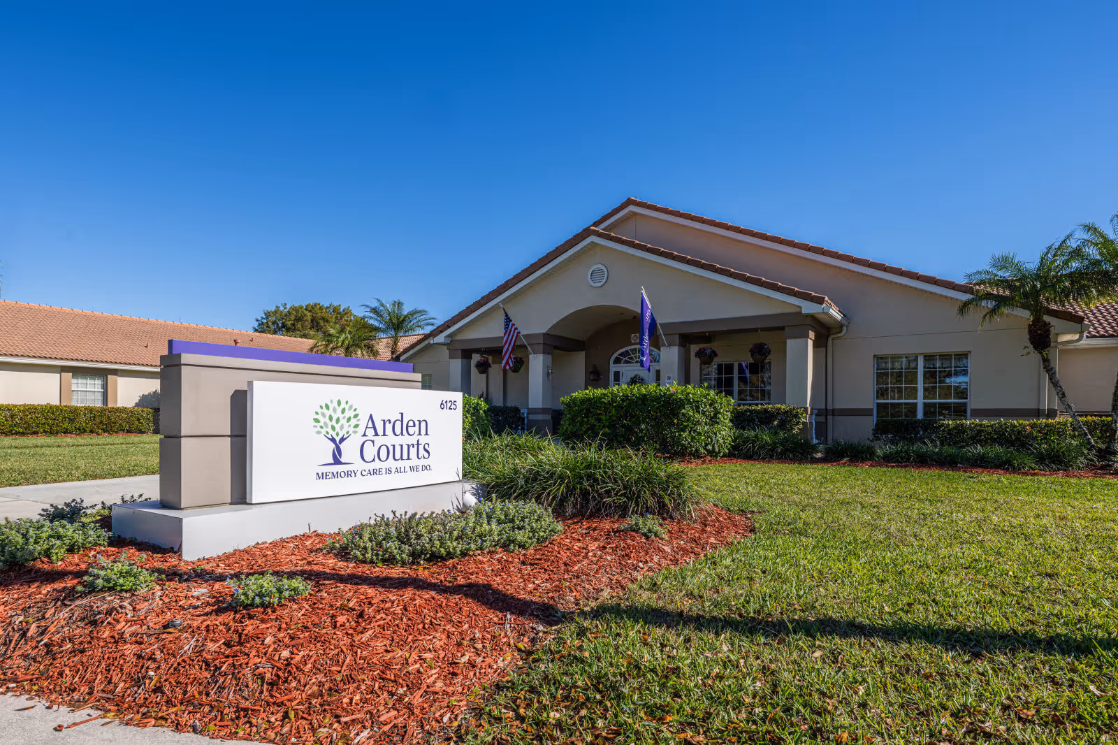 Arden Courts sign in foreground with a single-story building and manicured landscaping.
