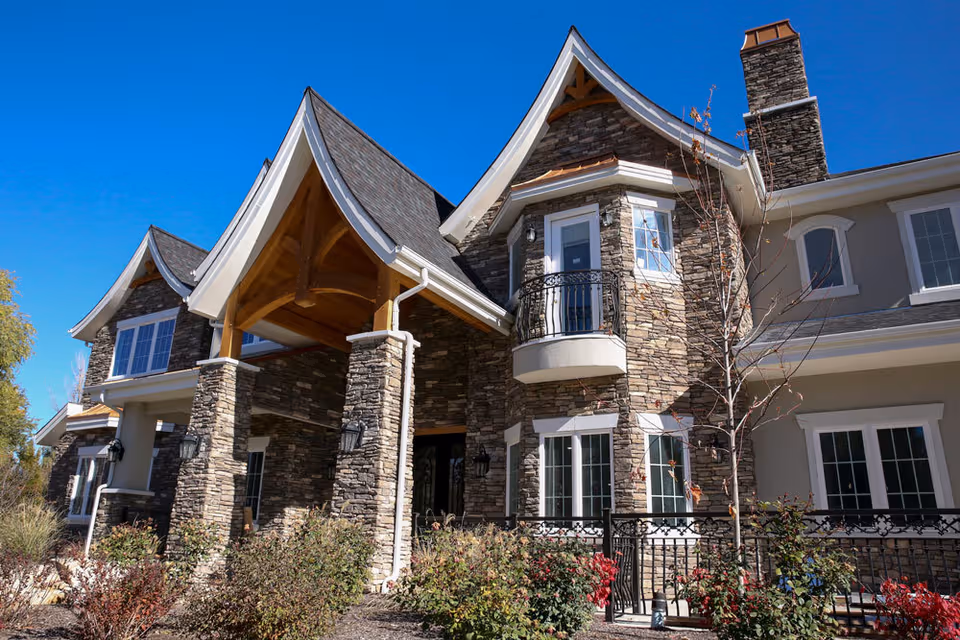 Front view of a stone-clad senior living facility with arched entry.