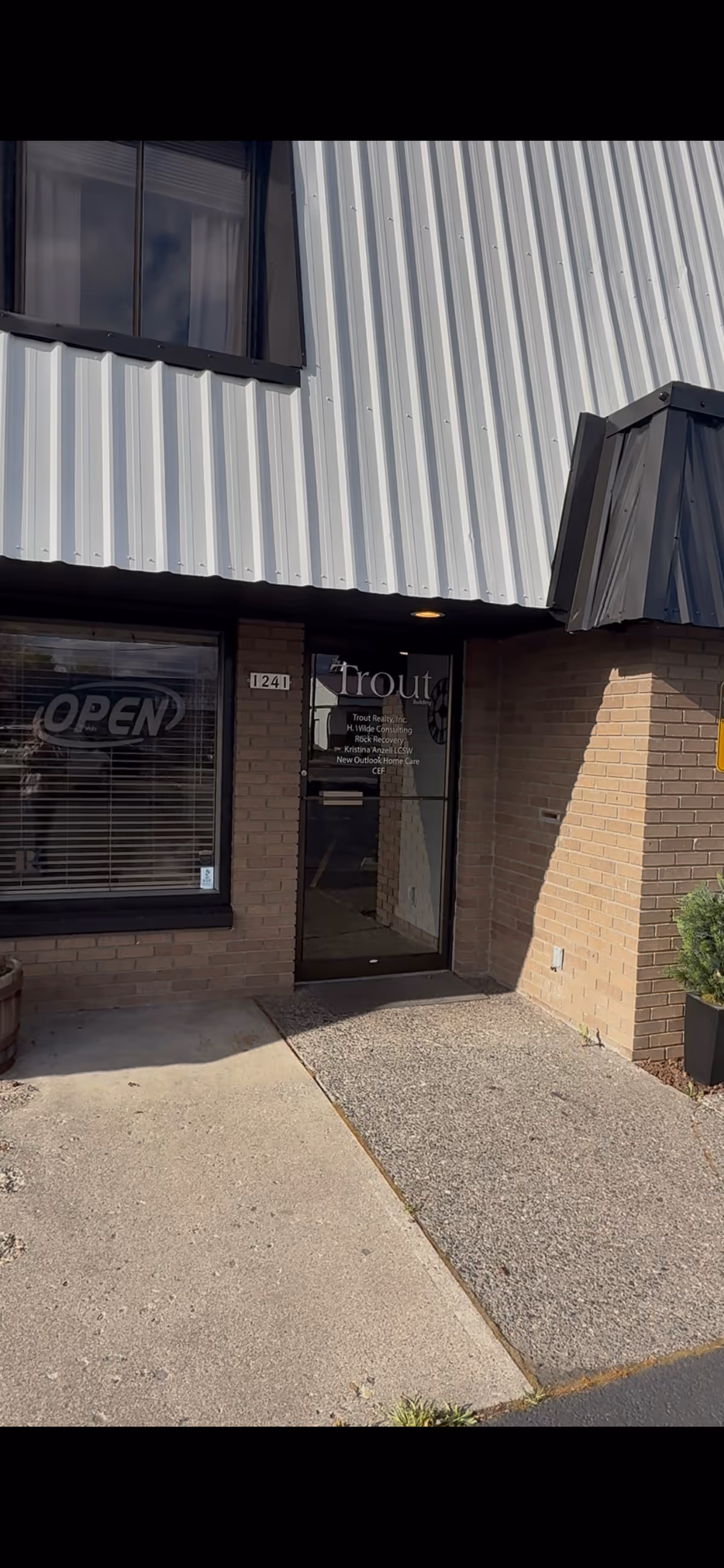 Front entrance of a brick and metal-clad building with glass door and window.