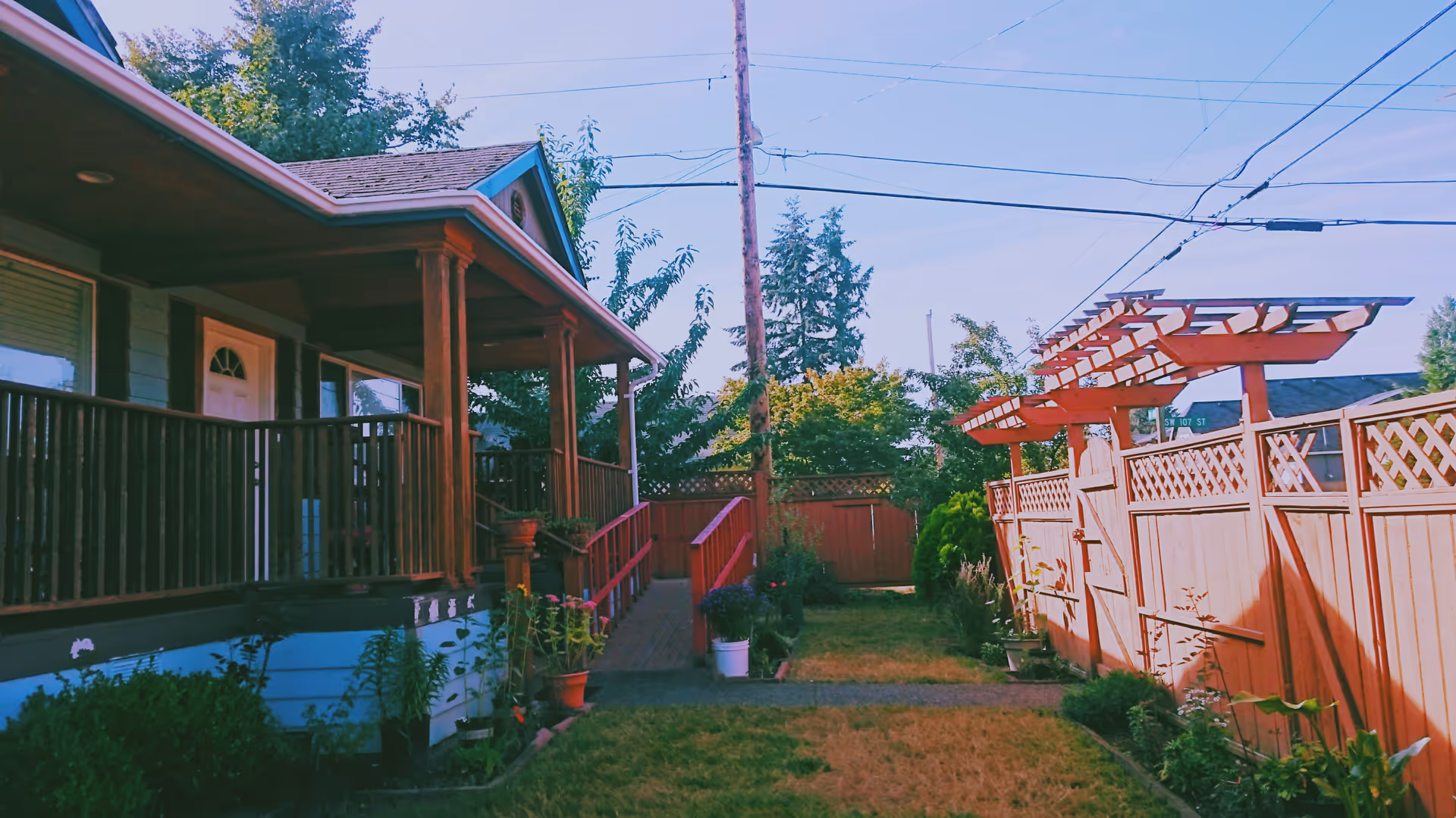 Front exterior of a single-story home with a wooden porch and fenced yard.