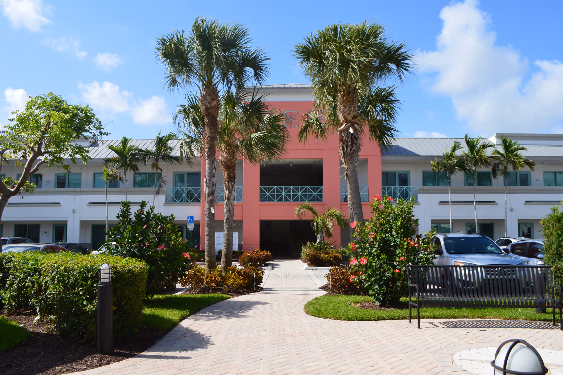 Front view of Home Instead of Palm Beach County, pink entrance, palm trees, and walkway.