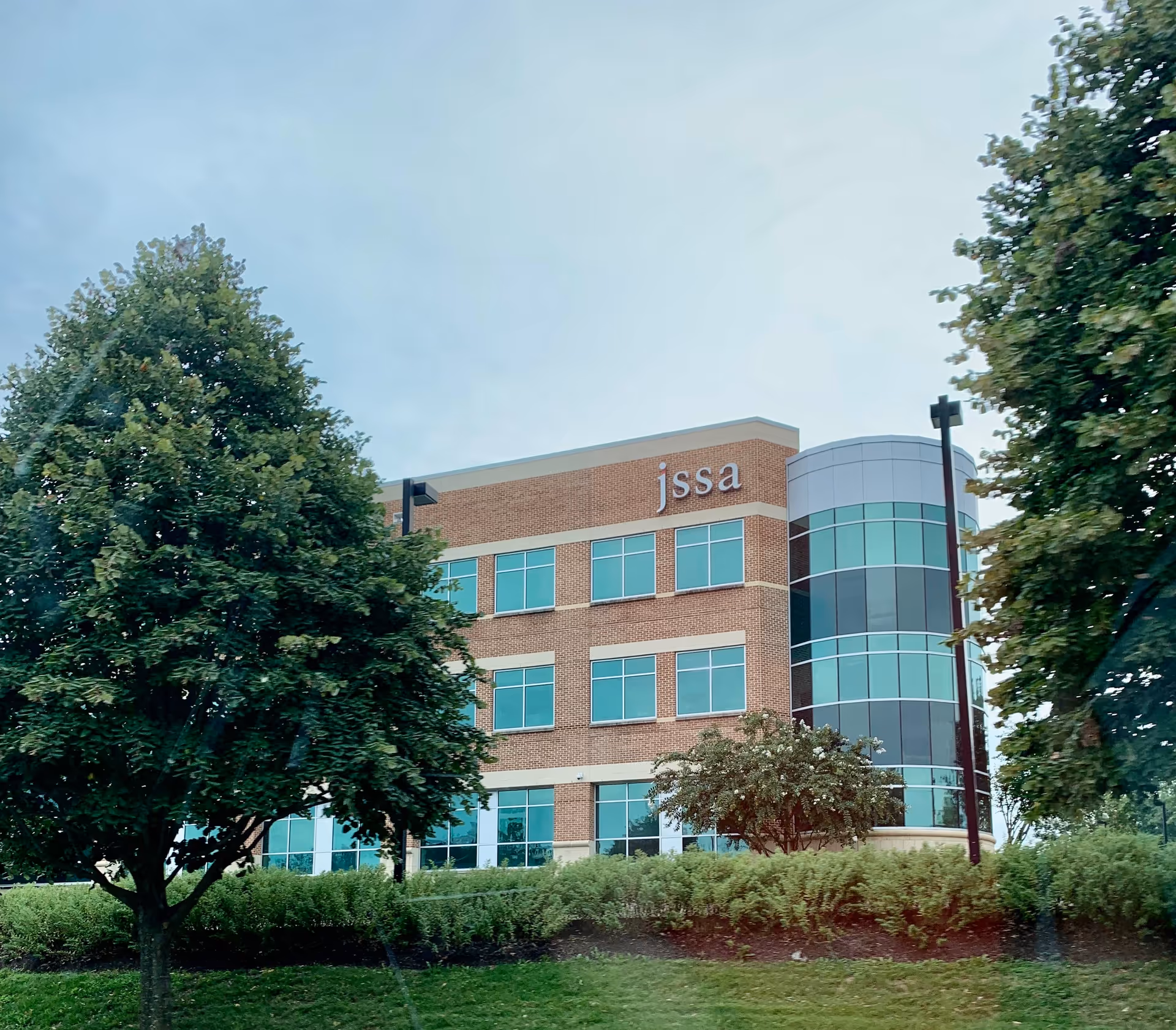 Exterior of a brick senior living facility with JSSA sign and curved glass entrance.