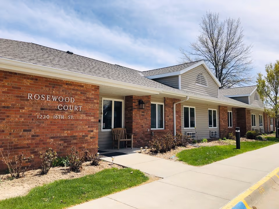 Exterior view of Rosewood Court senior living facility with brick walls and walkway.