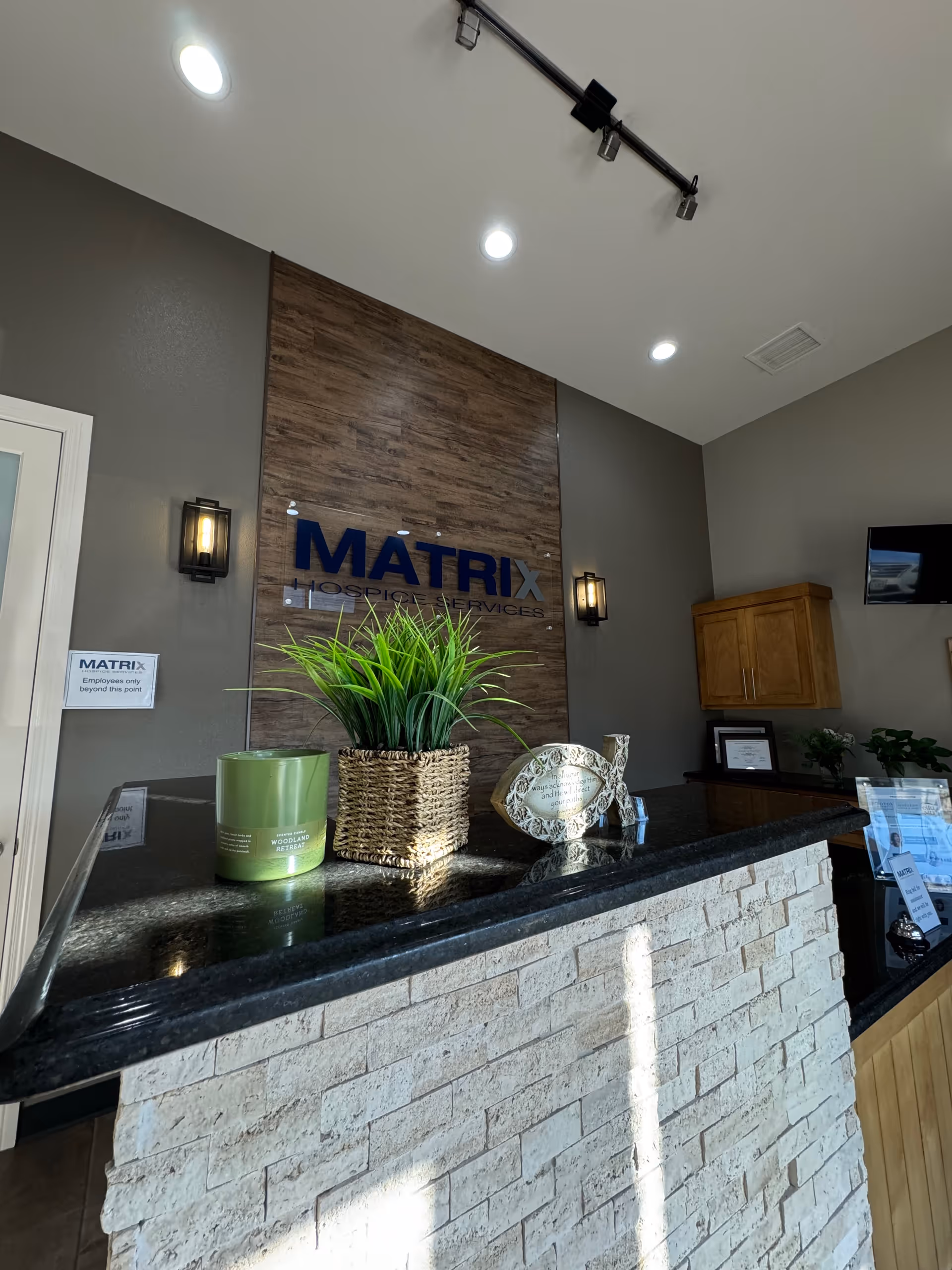 Lobby reception area with Matrix Hospice Services sign and plant on stone counter.