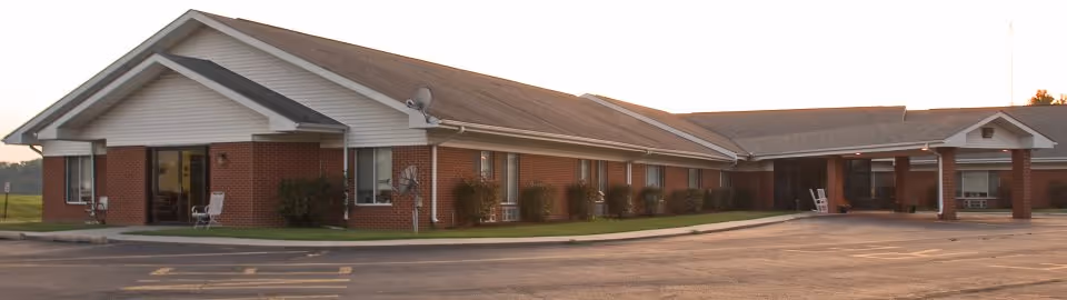 Single-story brick senior living facility exterior with a front entrance and adjacent parking.