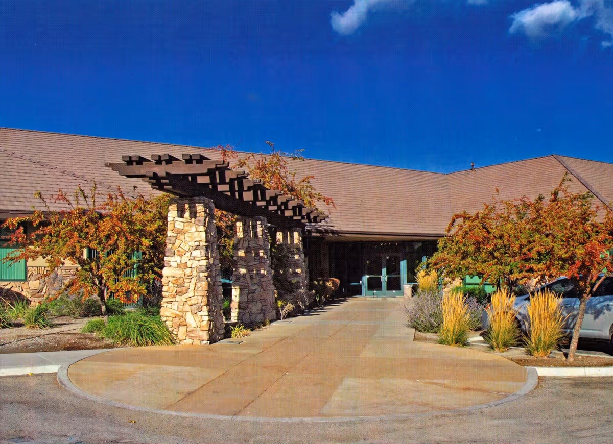 Exterior view of a hospice facility entrance with stone columns and pergola