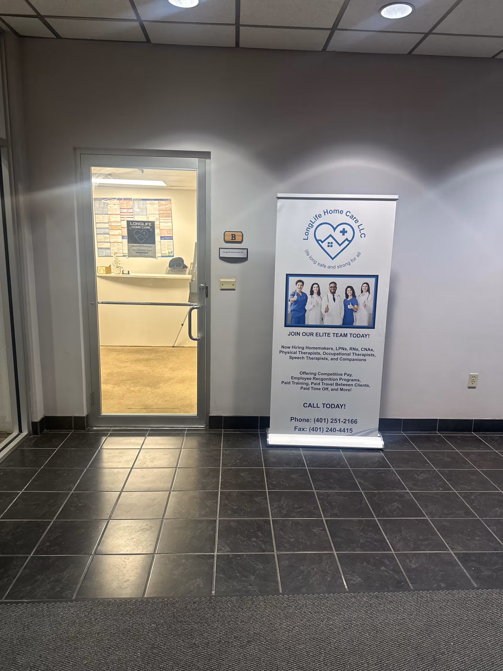 Interior hallway featuring a glass door, LongLife Home Care banner, and tiled floor.