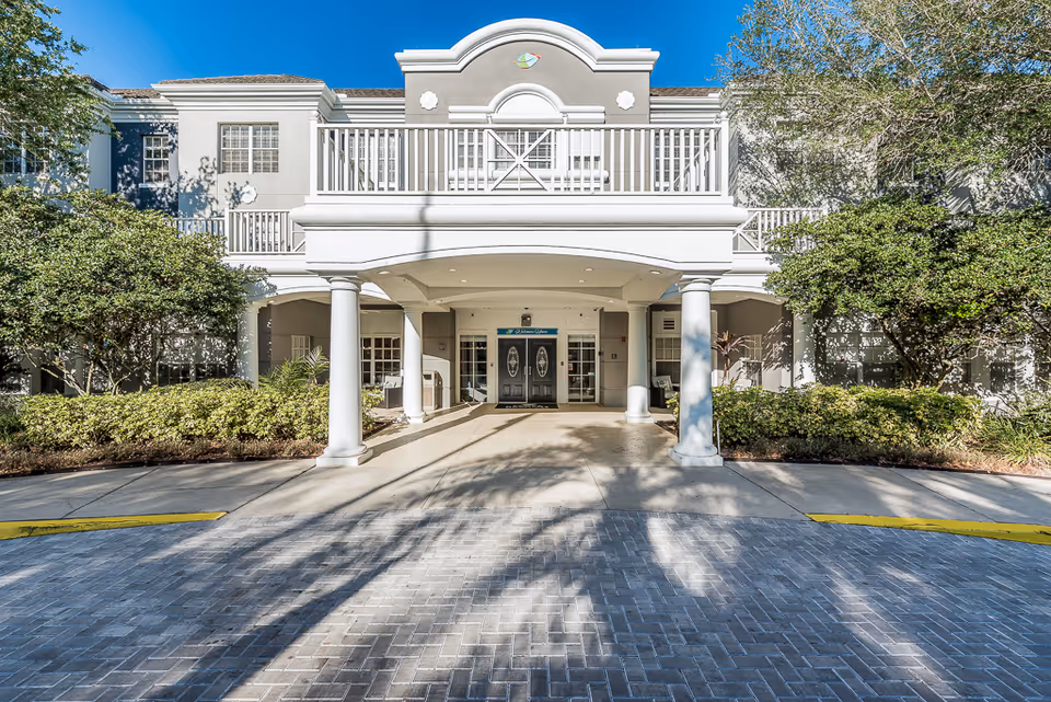 Front entrance of Tampa Gardens Senior Living building with white columns and covered entry
