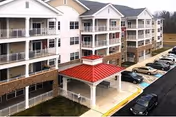 Exterior view of Conifer Village at Oakcrest with balconies and a red-roofed entrance.