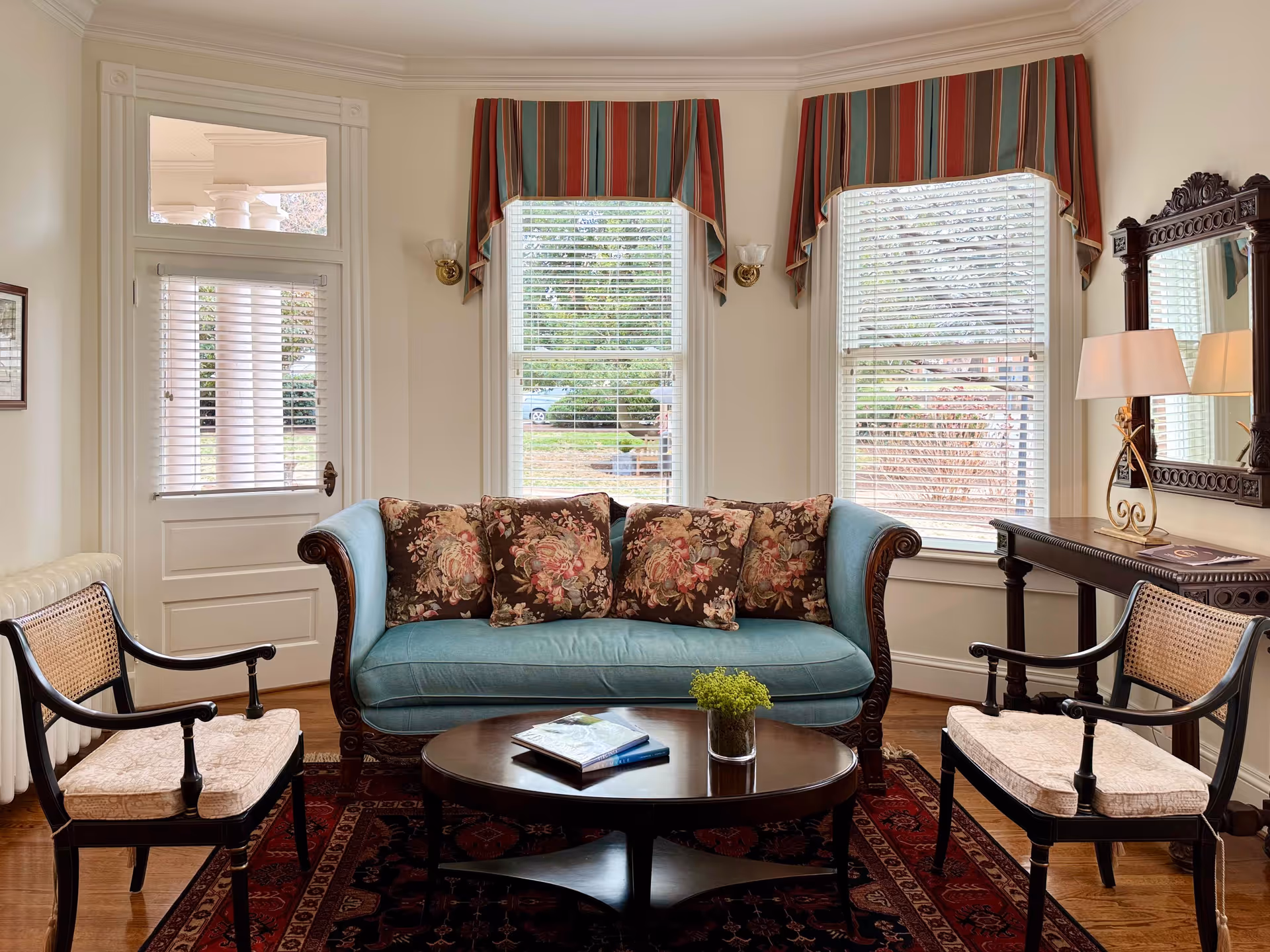 Cozy living room with a blue sofa, floral pillows, chairs, and a round coffee table.