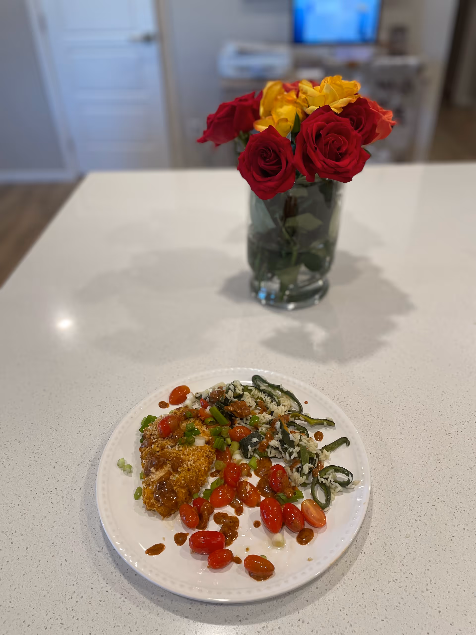 Colorful plate of mixed food on a kitchen island with a vase of roses in background.