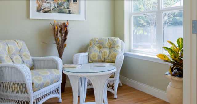 Bright wicker seating area with two armchairs, a glass table, and a window.