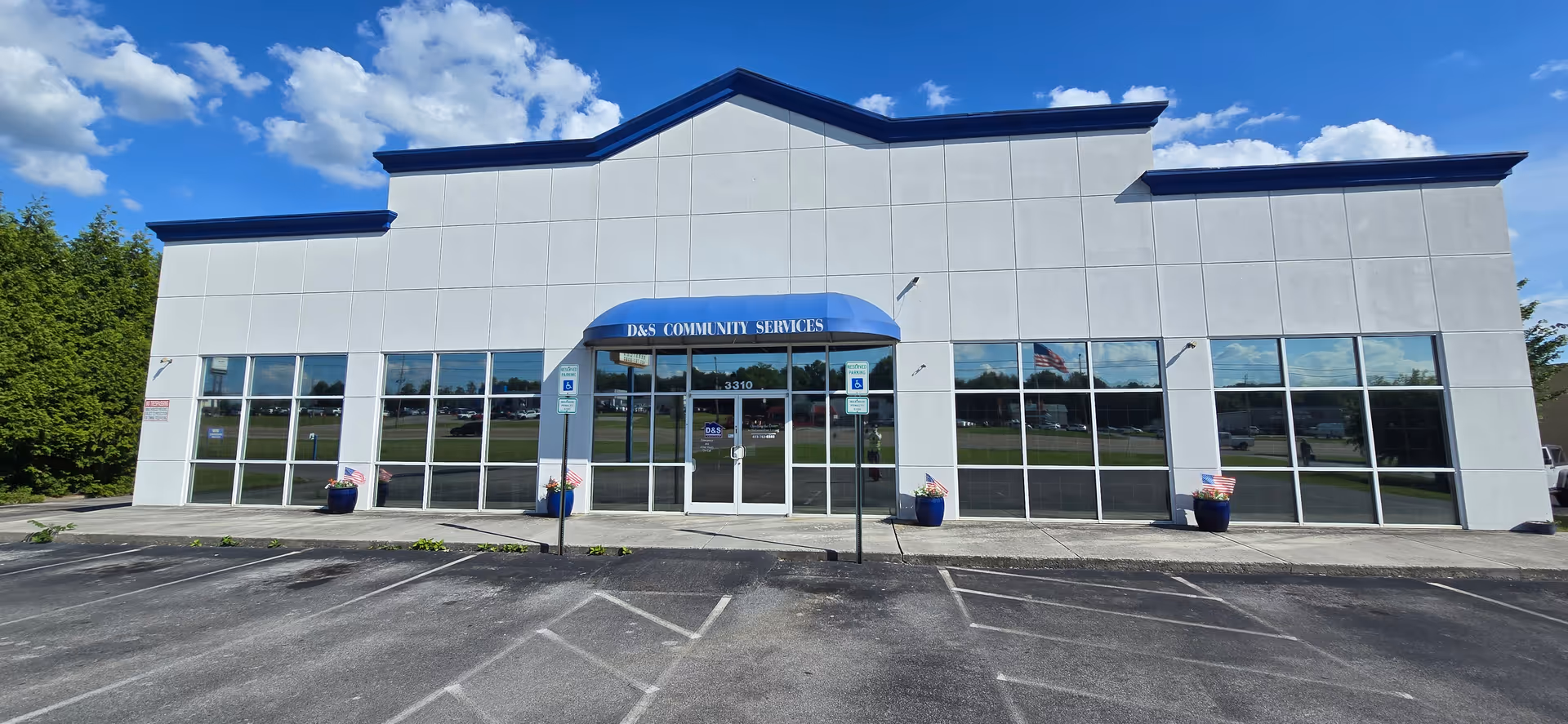 Modern, single-story facility with glass storefronts, blue curved awning, and accessible entrance.