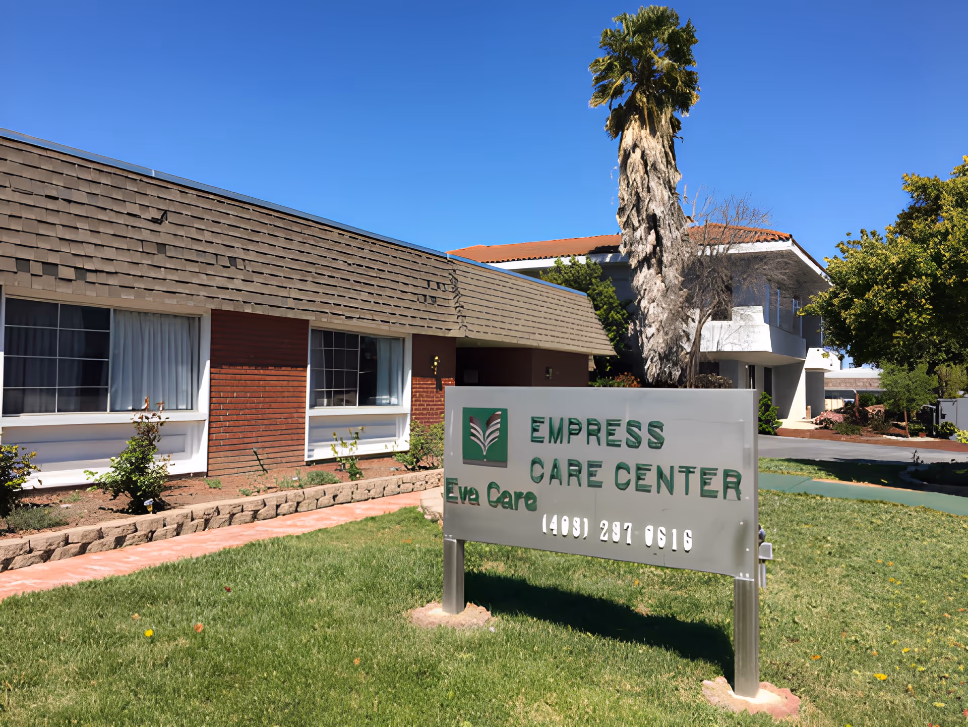 Front exterior of the Empress Care Center building with a lawn, palm tree, and a sign reading 'Empress Care Center' in the foreground.