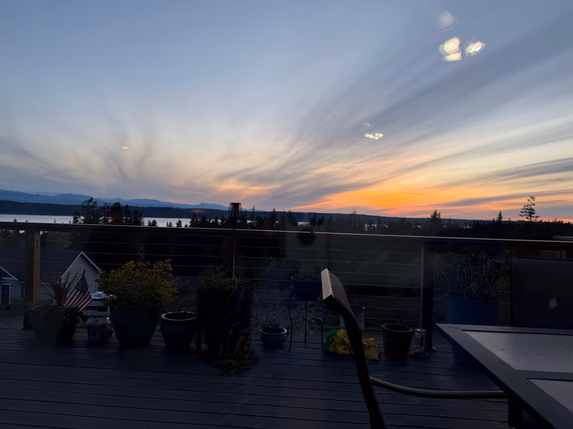 Outdoor deck with potted plants and furniture viewing sunset at Crest View Adult Family Home.