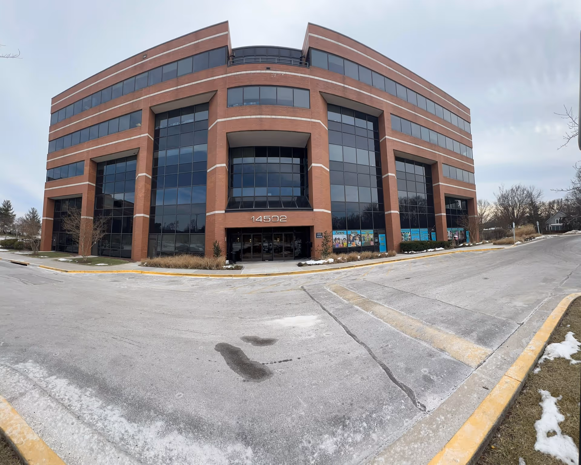 Large brick office building with tall glass windows and a curved central entrance.
