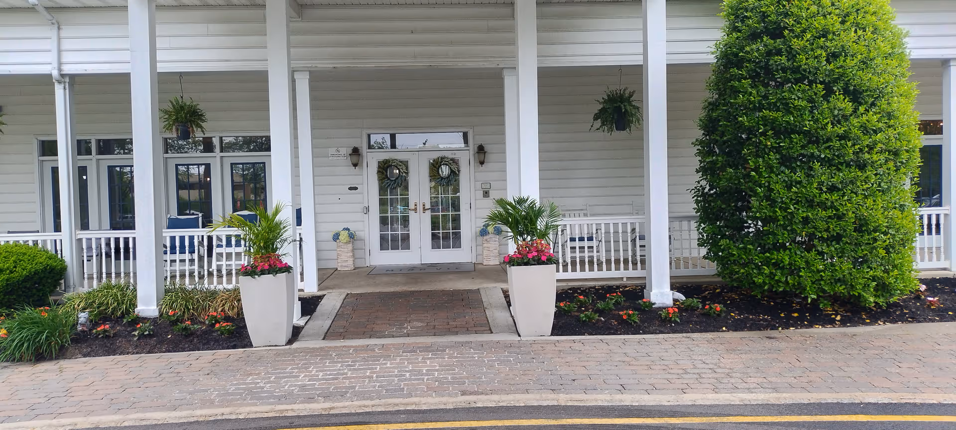 Exterior view of Mira Vie at Brick entrance with columns, planters, and landscaping.