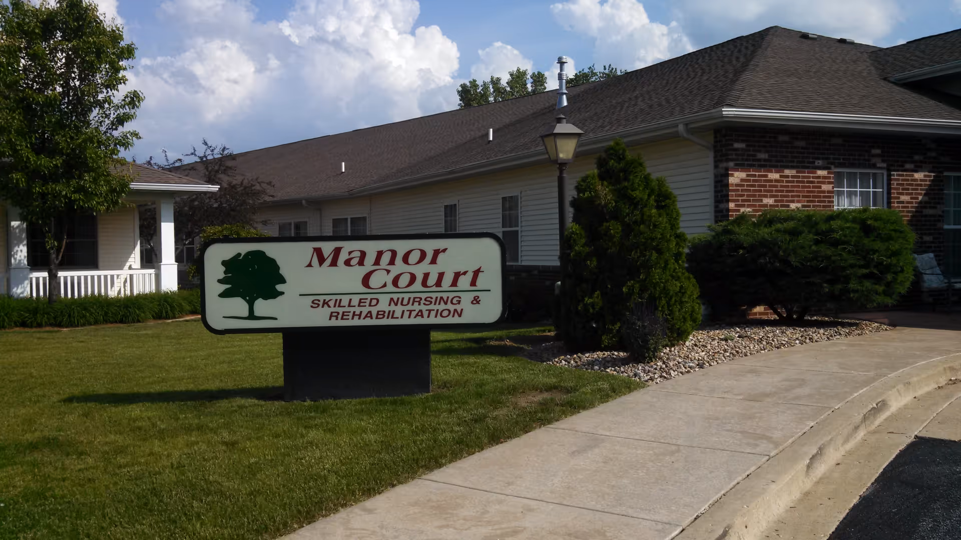 Exterior view of Manor Court facility with a large sign on a grassy lawn.