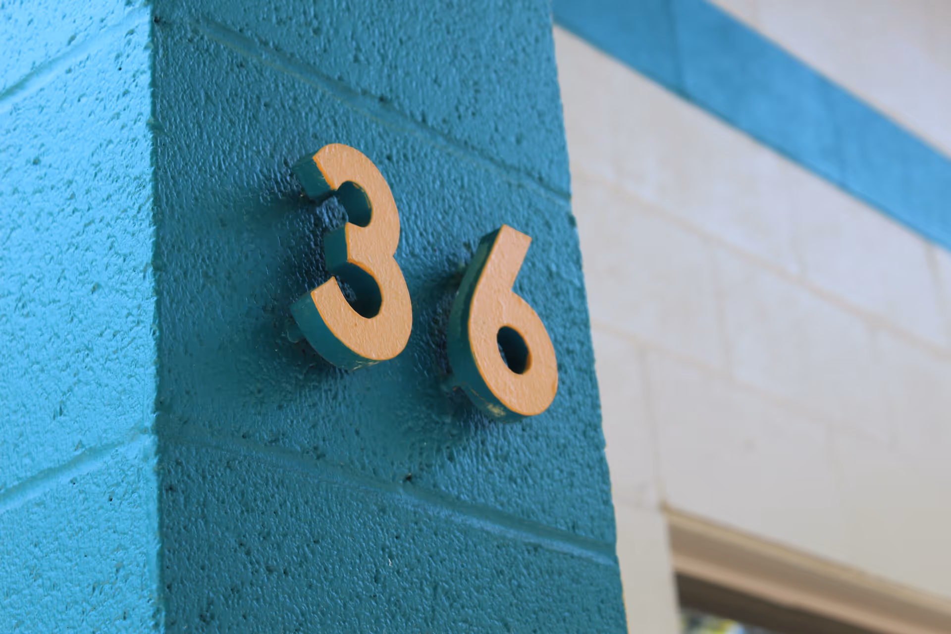 Close-up of a turquoise wall with gold numbers reading 36.