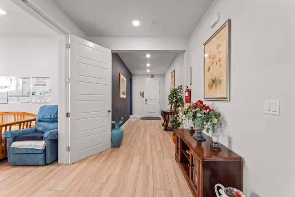 Bright interior hallway of Pinnacle Home Care Assisted Living with blue chair and floral console.