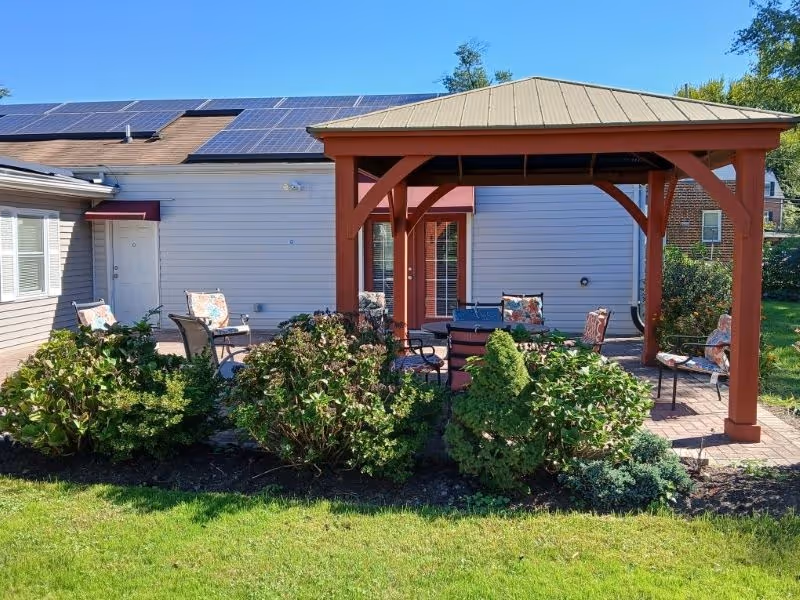 Outdoor seating area with a wooden pergola beside a single-story retirement home.