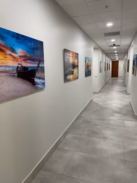 A well-lit hallway with framed seascape artwork along light-colored walls.