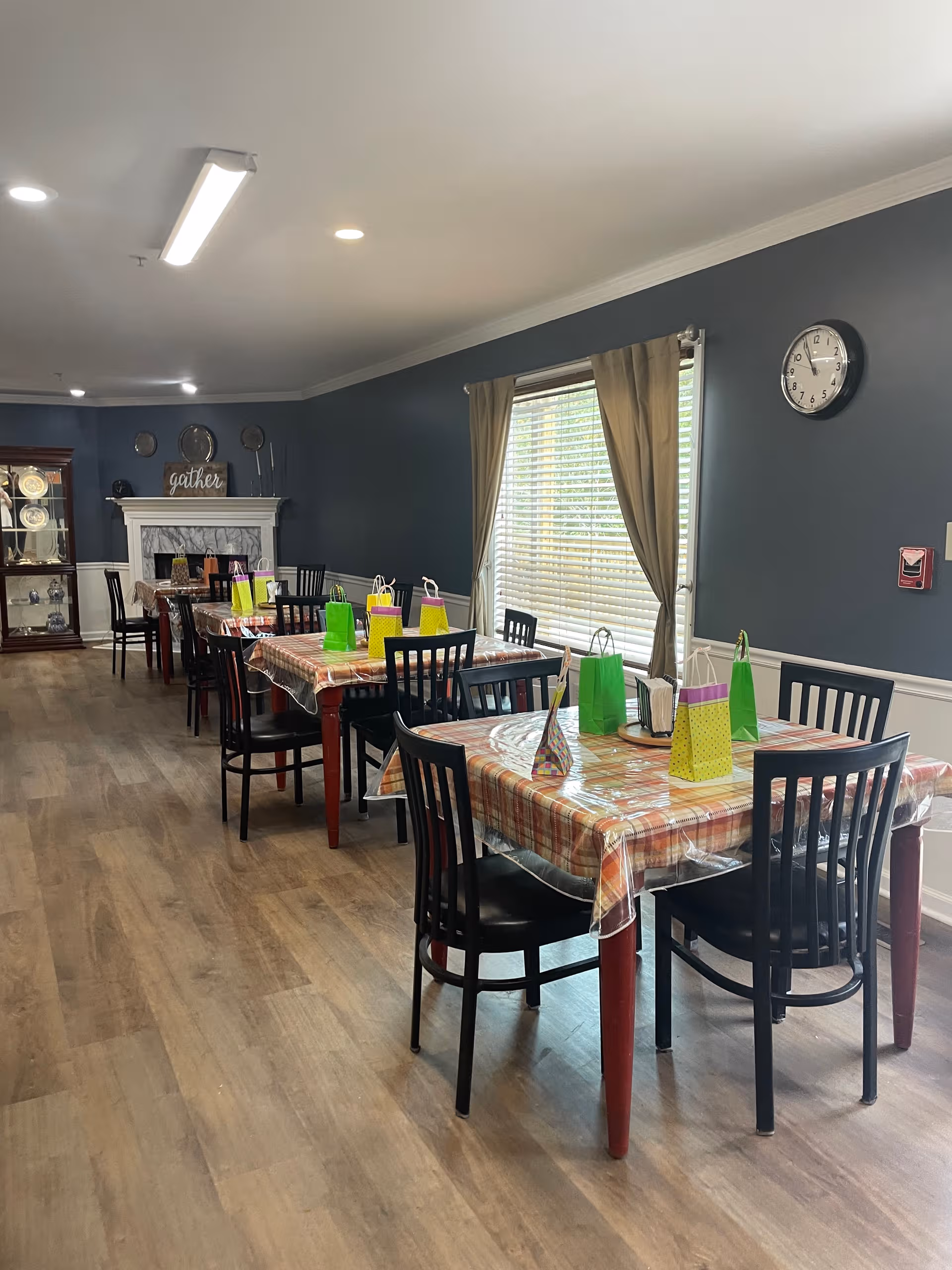 Senior living dining room with plaid tablecloths and colorful gift bags on tables.