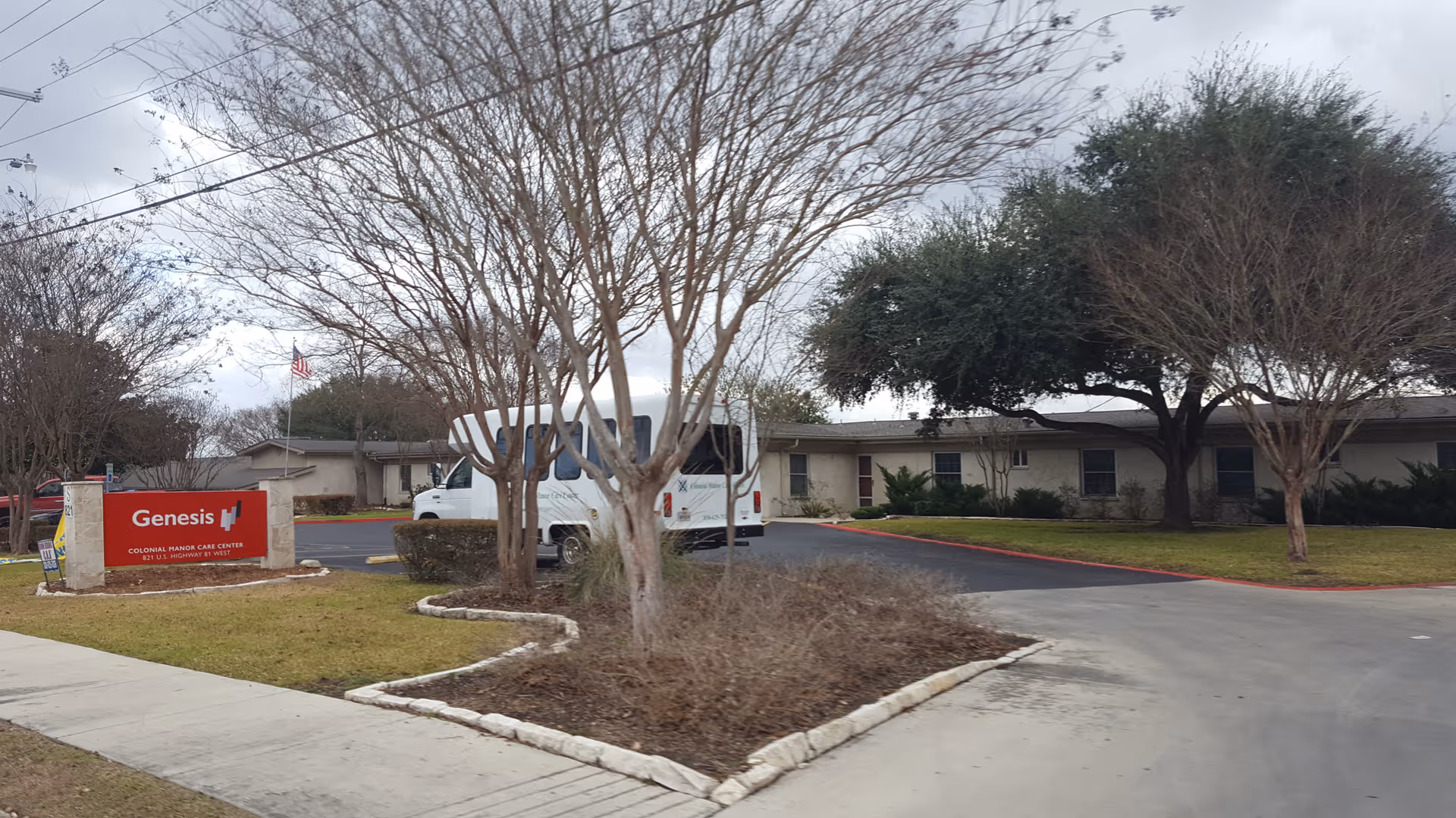 Exterior view of a senior living facility featuring a Genesis sign and a bus.
