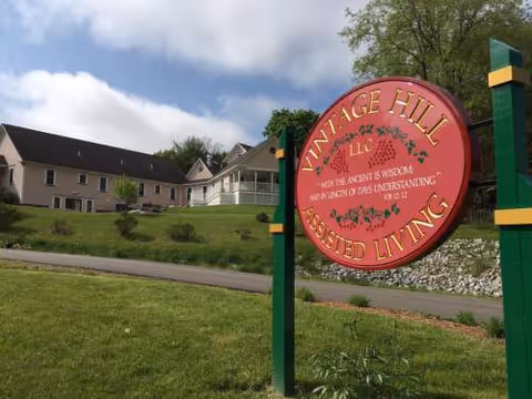 Vintage Hill Assisted Living exterior with a round red sign and a building in the background.