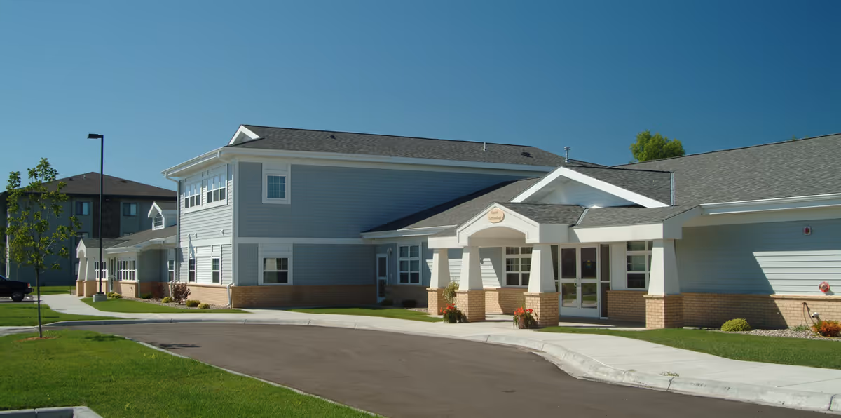 Exterior view of Autumn Grace senior living facility with entrance and landscaped walkway.