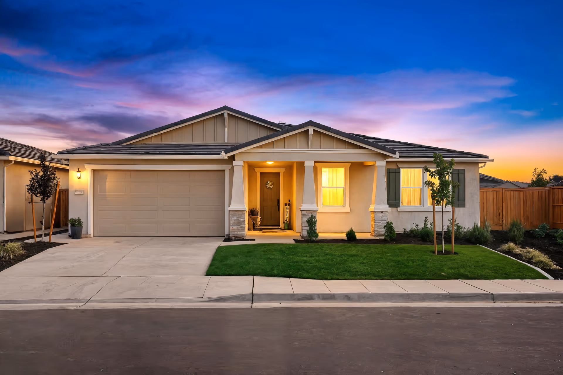 A single-story suburban home with a front yard, driveway, and garage at sunset.