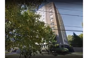 Tall brick senior living building with surrounding trees and overhead power lines.