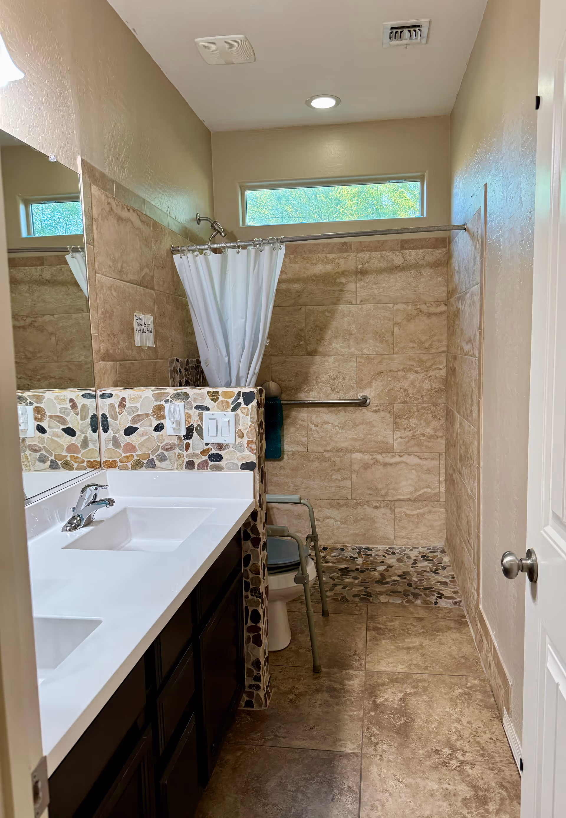 Bathroom with double sink vanity, mosaic tile accents, shower curtain, and accessible features.