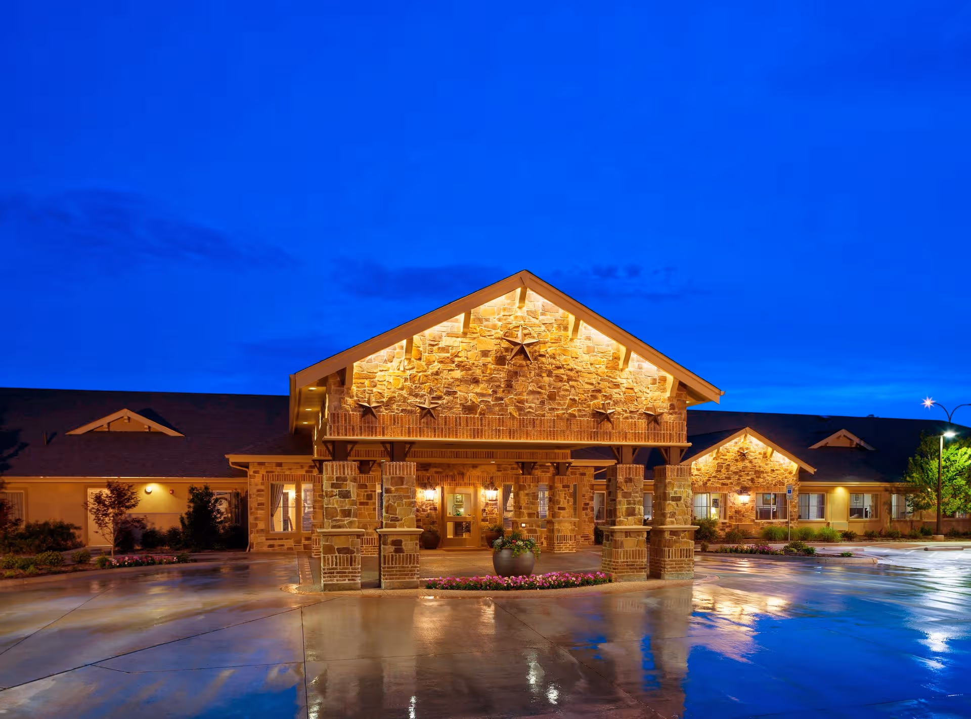 Nighttime exterior view of Meadowbrook Memory Care Community with a lit stone entrance.
