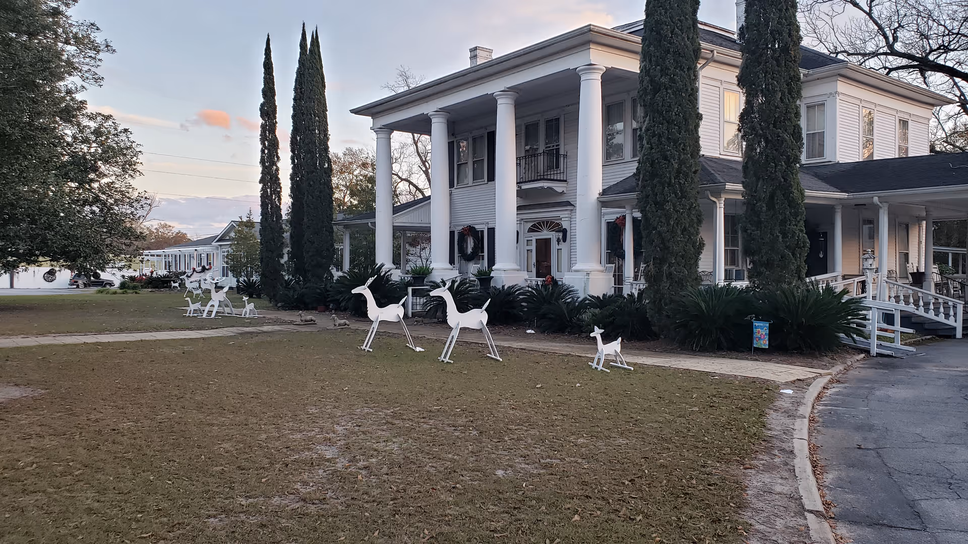 White columned building with a manicured lawn and white animal statues.