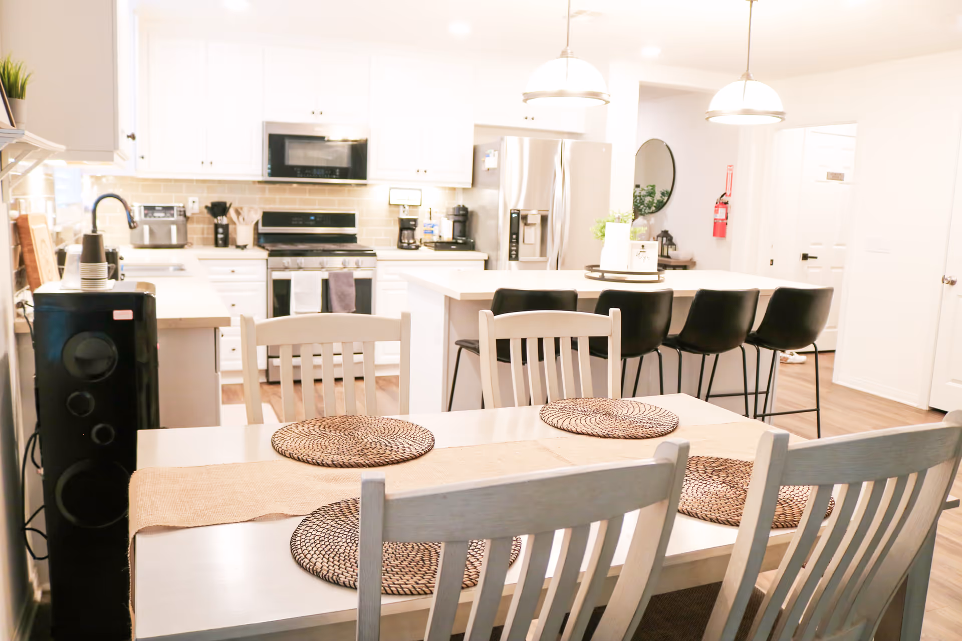 Bright open kitchen and dining area with white cabinets, island, and seating.