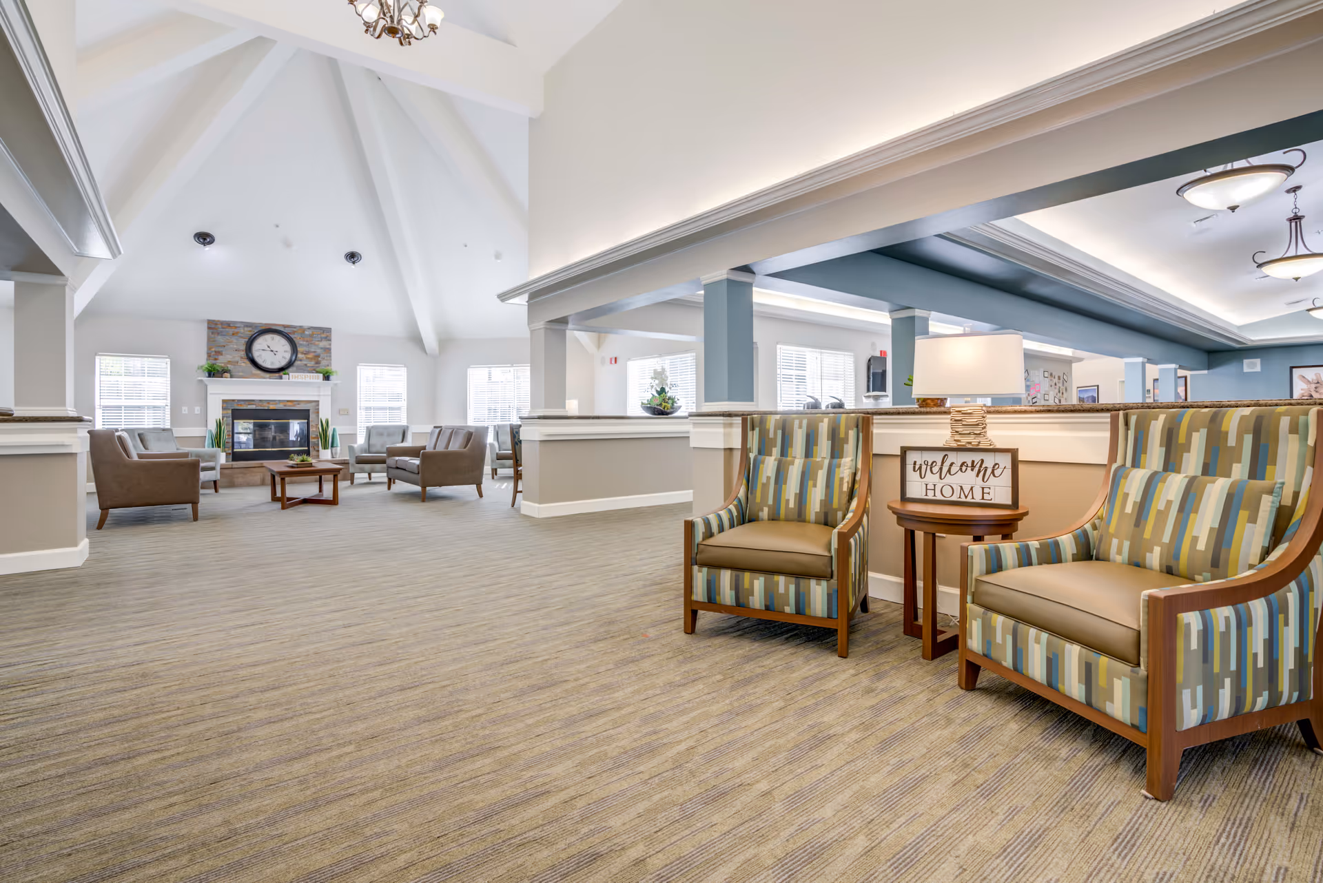 Spacious senior living lounge with chairs, a fireplace, and welcoming reception area.