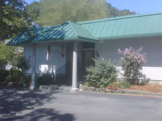 Front exterior of Retirement Center of Arkansas, a single-story building with green roof and entrance porch.