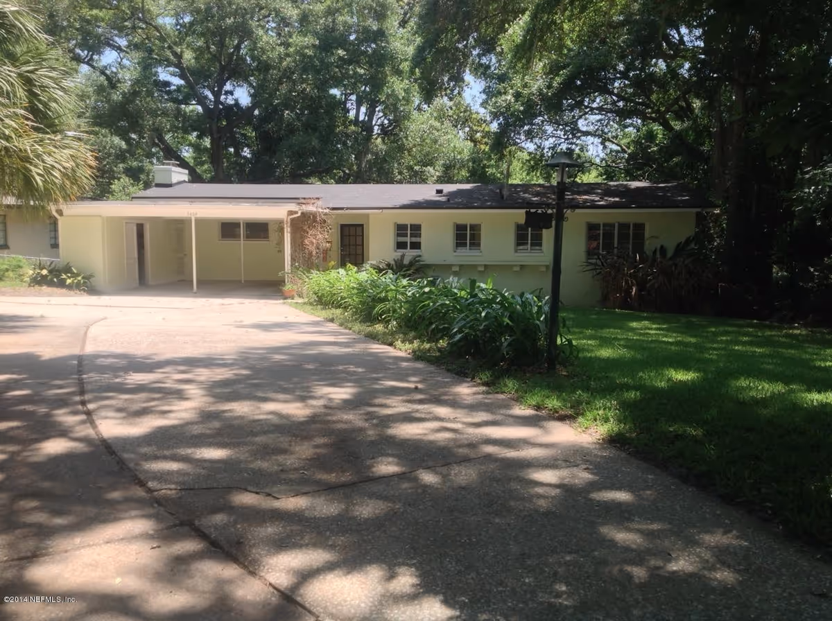 Single-story facility exterior with a curved driveway, green lawn, and trees surrounding.