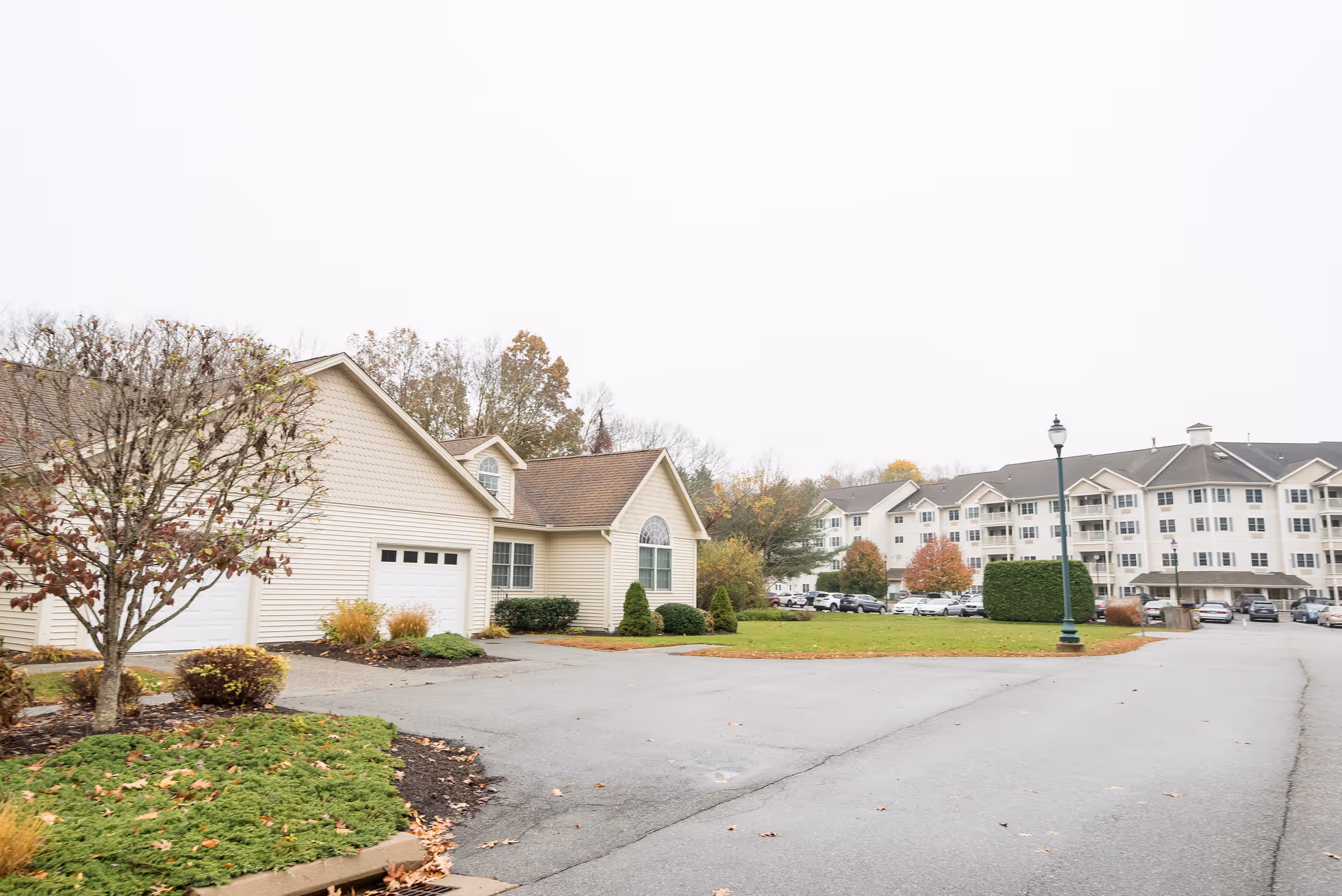 Exterior view of Creamery Brook Village with driveway, garages, and a lamppost along the road.