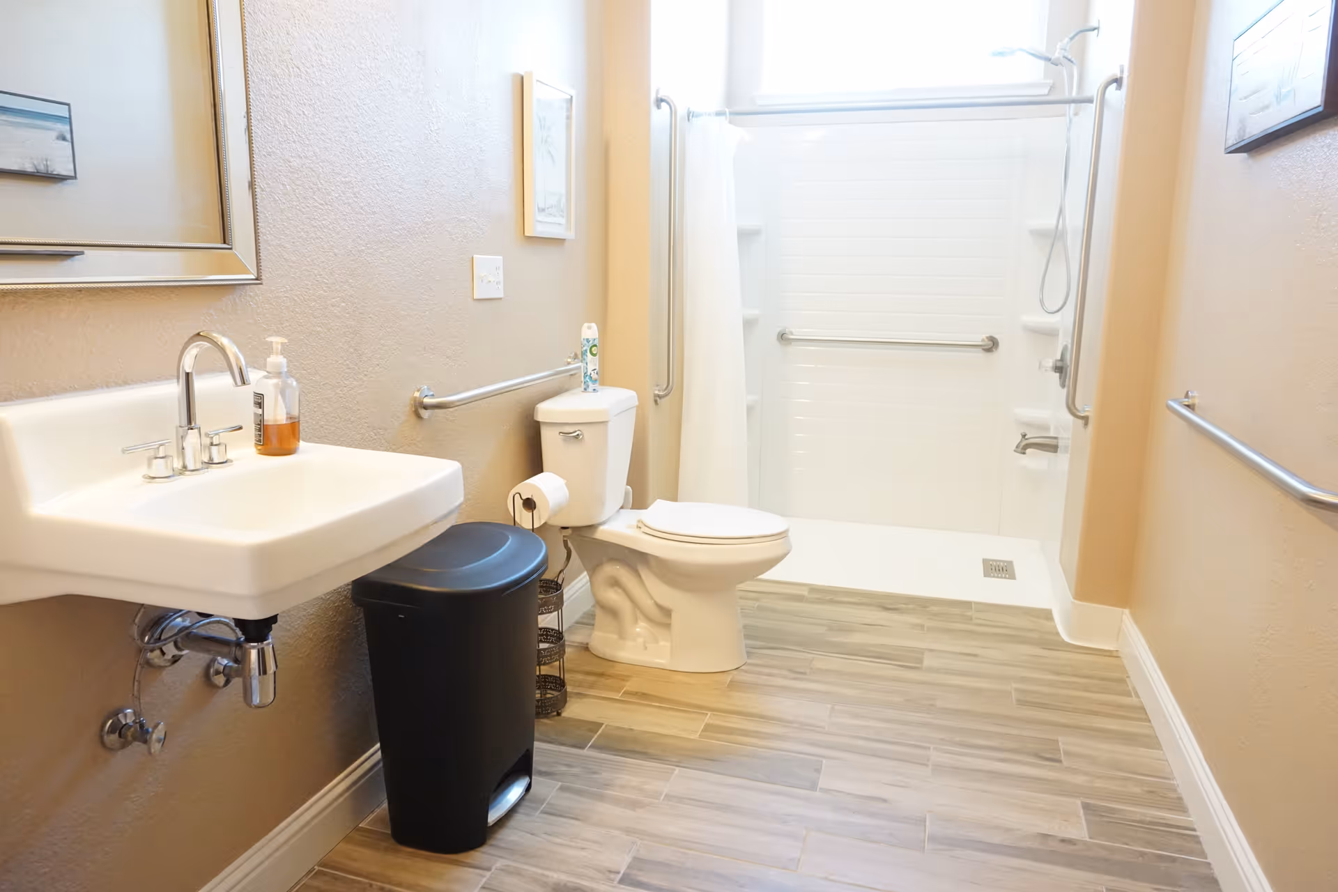 Accessible bathroom in a senior living facility with sink, toilet, grab bars, and walk-in shower.